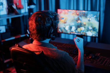 Genç oyun flamasının sunucu kanalı Moba ile savaş meydanında çoklu oyun takımıyla dövüşmeyi kazanıyor, bilgisayar monitöründe kulaklık takıyor ve neon dijital ışık modern odasında arka plan görüntüsü takıyor. Toplayıcı.