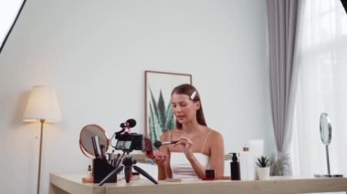Sosyal medya için güzellik ve kozmetik video içeriği hazırlayan genç bir kadın. Güzellik blogcusu kameraya gülümserken seyircilere ve takipçilere güzellik bakımını gösteriyor. Düzenle