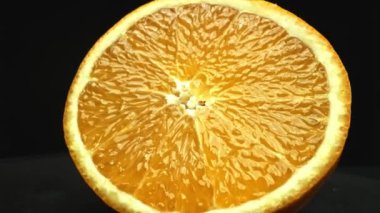 Portakal diliminin bir makrografi görüntüsü, parlak, izole edilmiş bir arkaplan üzerine yerleştirilmiş, narenciye cazibesinin görsel bir başyapıtı olarak gözler önüne seriliyor. Siyah arkaplanlı bir dilim portakal. Geliştirilebilir.