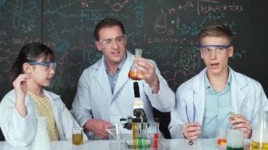 Akıllı öğretmen deney kabında çözeltiyi tutarken öğrenci BTMM fen dersinde kimya teorisiyle karatahta deney yapıyor. Kimyasal sıvıyı laboratuvarda inceleyen yetenekli bir bilim adamı. Öğretim