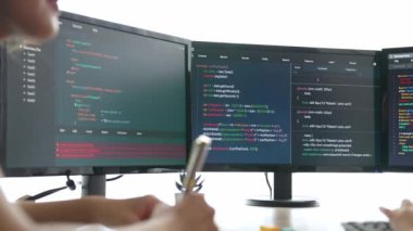 Yavaş çekim arkası yazılım geliştirici mühendisi bilgisayar programlama için birlikte çalışarak hata ayıklama kodunu çözüyor, ofiste monitörde karmaşık algoritmaları çözüyor. Filizlenen