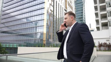Yetenekli bir iş adamı pazarlama ekibiyle pazarlama stratejisi hakkında konuşurken gökdelende dururken telefon kullanıyor. Mutlu yönetici, modern kentsel şehirdeki satışları arttırmak için meslektaşını arıyor. Urbane.