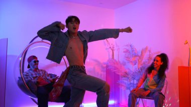 Çok kültürlü bir arkadaş kürsüde otururken Asyalı yetenekli bir dansçı modern müziğe geçiyor. Profesyonel dansçı, hipster takımı tezahürat yaparken ve desteklerken enerjik adımlar atıyor. Mutluluk.