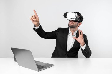 Bilgisayarla masada otururken ve VR gözlüğü takarken veri analizine bakan yetenekli bir iş adamı. Proje yöneticisi sanal gerçeklik sistemini kullanarak ya da metaevrende bağlantı kurarak çalışıyor. Sapma.