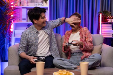 Oyun oynayan mutlu çiftin oturduğu kanepe joystickle oyun oynuyordu. Önden atıştırmalıklar ve kazanmak için gözlerini kapayan içkiler, evdeki modern neon ışıklı oturma odasında eğlenceli bir şekilde meydan okumaydı. İnfobahn.