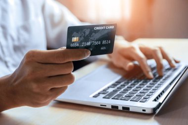Genç adam, laptop bilgisayar başvurusu ya da web sitesinde online alışveriş yapmak için kredi kartı kullanıyor. E-ticaret ve online alışveriş konsepti. uds