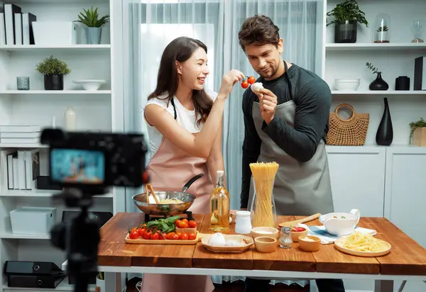 stock image Couple chef influencers on cooking show presenting ingredient of spaghetti, meat, chilli, tomato, garlic and seasoning sauces homemade special recipe recording on camera on live channel. Postulate.