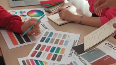 Not defterine yeni tasarım taslağı hazırlayan ve projeyi denetleyen müşteriyle renk seçimi yapan iki tasarımcının yavaş çekim çekimi. Tasarımcı bürosunda kromatik danışma. Değiştirilmiş