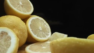 Limon dilimleri titizlikle koyu siyah bir yüzey üzerinde kırsal bir sepetin arka planına dizilmiştir. Her dilim, yumuşak ışıkla kaplanmış arka planda, Makrografi. Geliştirilebilir.