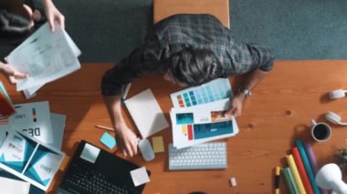 Tasarımcı yazma fikri ekrana bakarken proje yöneticisinin üst görünümü. Akıllı iş adamlarını kapat ve tasarımcı palete bakarken logo tasarımı fikrini açıkla. Sempozyum.