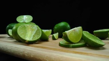 Yakın plan, canlı bir dilim taze kireç kırsal bir ahşap kesme tahtasının üzerinde duruyor. Tazelik ve canlılık yayıyor. Kesme tahtasına konmuş yeşil limon diliminin yarı saydam zarları. Geliştirilebilir.