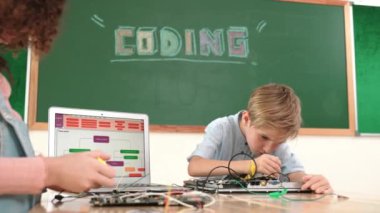 Kafkas akıllı çocuk kök teknoloji dersinde tornavida kullanarak ana tahtayı tamir ederken aynı zamanda gülümseyen öğrenci de dizüstü bilgisayar ekranı kodlu elektronik makineyi incelemek için birlikte çalışıyor. Pedagoji.