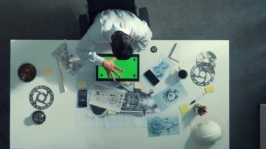 Türbin motoru veya jet motoru tasarımı ve çeşitli metal teçhizat dağılımı ile toplantı masasında yeşil ekranlı tablet üzerinde çalışırken telefona bakan mühendis görüntüsü. Hizalama.