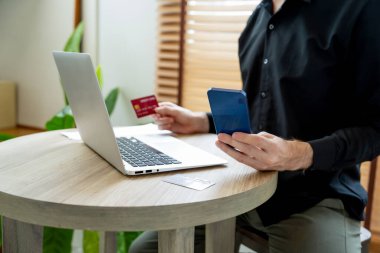 Genç adam internet bankacılığı için kredi kartlı dizüstü bilgisayar kullanıyor. İnternet üzerinden alışveriş yapıyor. Banka kartıyla modern ve kullanışlı online satın alma. Açılıyor