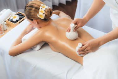 Sıcak bitkisel top spa masaj vücut tedavisi, masör kadın vücuduna nazikçe şifalı bitki torbası bastırıyor. Aromaterapi dinlenme sükuneti ve sükuneti kaplıca salonundaki atmosferi aydınlatıyor. Sessiz.