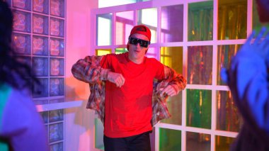 Kafkas dansçısı dans ederken çeşitli arkadaşları gece kulübünde neon ışıkta ayak seslerine bakıyor. Çoklu etnik kökenli hipsterin serbest stil müziğe geçişi ve mutlu bir adamın kameraya bakışıyla. Mutluluk.