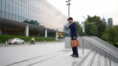 Profesyonel proje yöneticisinin iş yerine giderken elinde çantayla parkta ya da şehirde yürüyen yetenekli bir iş adamı. Büyümeyi temsil et, terfi al, yeteneğini arttır. Sevinçli..