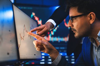 Hisse senedi tüccarı en yüksek hisse senedi piyasasını dinamik değerli analize işaret ediyor. Gerçek zamanlı ekranda iş arkadaşı var. Borsa için finans şirketinde iş birliği yapıyor. Satılabilir.