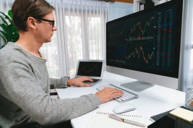 Bilgisayar ve dizüstü bilgisayarı kullanarak, çalışma masasındaki dinamik artırılmış borsa grafiğinin en yüksek kar değerini araştıran bir tüccar, modern ofisteki ekrandaki döviz kuru değerini analiz ediyor. Bireysel.