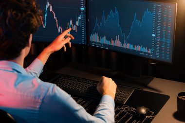 Piyasa stok grafik veri planlama üzerine çalışan genç tüccar Neon Modern Ofis 'te arka taraf görüşü ile gerçek zamanlı izleme yapıyor. Dinamik para bozdurma oranını analiz etme kavramı. Toplayıcı.