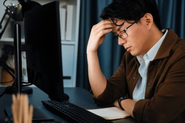 Stresli yüzü olan akıllı işadamı, gece geç saatlerde ofiste iş planı raporu hazırlamak için bilgisayar üzerinde çalışıyor ve yeni bir şirket kurma projesi için araç pazarı planlaması üzerinde çalışıyor. İnfobahn.