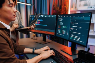 Modern ofisteki neon ışık odasında bilgi ağını gösteren dizüstü bilgisayarla iki ekranda veri çalıştıran akıllı web sitesi geliştirme kodlayıcı sistemini tartışan IT geliştiricilerinin ciddiyeti. İnfobahn.