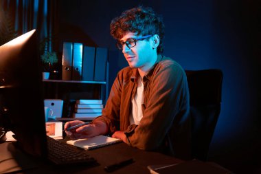 Genç işadamı, Neon Light Modern Ofis 'te yaratıcı bir başlangıç projesi için bilgisayara odaklanıyor. Düşünüyorum da, pazarlama ağı yaratıcıdan pazar kanalı tasarım konseptine çevrimiçi planlama. Toplayıcı.