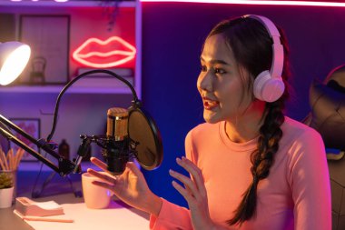 Geceleri podcast 'te olumlu konuşmalar yapan, pembe neon ışıklı modern stüdyoda sunum için dizüstü bilgisayar kullanan, gülümseyen, genç, güzel Asyalı bir etkileyiciydi. Taktik.