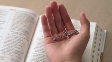 Hristiyan katolik takipçilerle dinsel bağlılık ve maneviyat duygusu doludur. Ağır çekimde el, kutsal İncil 'i nazikçe tutar ve dini dua ve Hıristiyanlık eğitimi için çaprazlar. Filizlenen