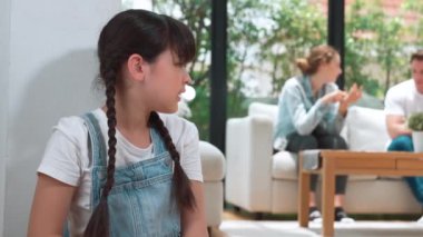 Stresli ve mutsuz genç kız köşeye kıvrılıp kulaklarını kapatarak arka planda ebeveyninin tartışmasını engelliyor. Evde aile içi şiddet ve travmatik çocukluk depresyona dönüşür. Titiz