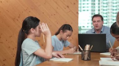 Akıllı öğrenci çalışmalarını kontrol ettiği için mutlu öğretmen diye el kaldırdı. Liseli kız not defterine bakan yetenekli bir öğretmen ve sınıfta onu cesaretlendiren bir başparmak gösteriyor. Yaratıcı. Öğretim