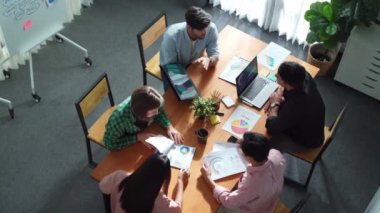 Proje yöneticisinin üst görünümü toplantıda yatırımcılara mali grafik sunuyor. Profesyonel pazarlama ekibi dizüstü bilgisayardan finansal istatistiklere bakarken finansal fikir üretiyor. Cemaat.