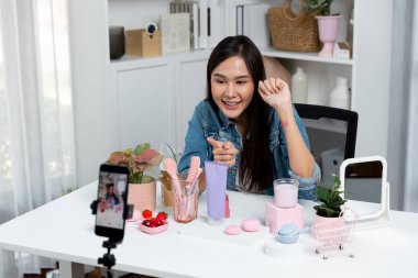 Genç, güzel Asyalı kozmetik makyaj ruju matte pastel rengini modern odadaki sosyal medyada kol testi tanıtımında en çok satanlar listesinde gösteriyor. Taktik.