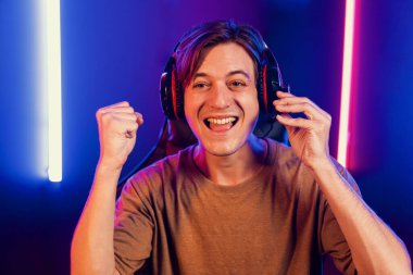 Kazanmak için çevrimiçi oyun oynayan akıllı flama makinesinin sunucu kanalı, neon ışıklı odada seçilen takım yarışması için izleyicilerle birlikte canlı yayında canlı yayında kulaklık takıyor. Bireysel.