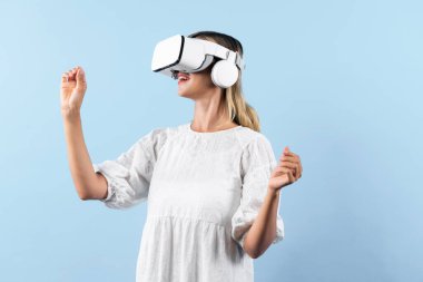 Kız çiçeğin kokusunu alırken mavi arka planda sanal gerçeklik gözlüğü takıyor. VR gözlüklü mutlu kadın görsel gerçeklik dünyasıyla bağlantı kurarken doğa hologramının keyfini çıkar. Teknoloji yeniliği. Kısıtlanma.