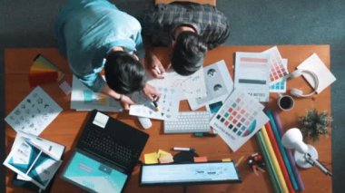 Akıllı tasarımcının renkli paletlerden renk seçmesine yardım ederken yukarıdan aşağı görünümü. Dizüstü bilgisayardan logoya bakarken birlikte çalışan ve planlayan iş adamlarının hava görüntüsü. Sempozyum.