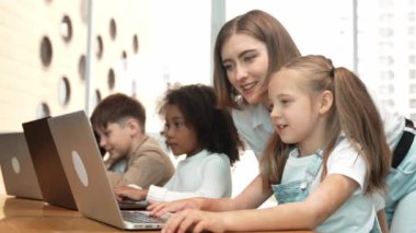 Çok kültürlü bir öğrenci dizüstü bilgisayar kullanarak mühendislik kodları yazarken öğretmen program hakkında açıklama ve öğretim yapıyor. Profesyonel eğitmen BTMM sınıfında programlama sistemini öğrenmeye yardım ediyor. Etkinlik.