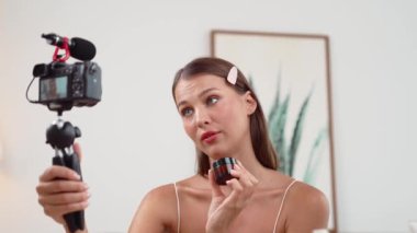 Sosyal medya için güzellik ve kozmetik video içeriği hazırlayan genç bir kadın. Güzellik blogcusu kameraya gülümserken seyircilere ve takipçilere güzellik bakımını gösteriyor. Düzenle