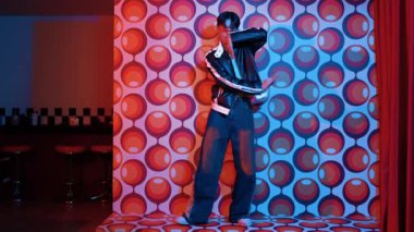 Asyalı break dansçı serbest stile geçiyor ve balon arka planlı kameraya bakıyor. Profesyonel hippi gündelik kıyafet giyer ve gözlük takar. Mutluluk.