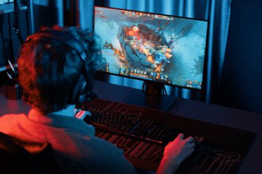 Savaş arenasında çoklu oyunlar takımıyla Moba 'da savaşan genç oyun flamasının sunucu kanalı, neon dijital ışık modern odasındaki arka görüntü ile bilgisayar monitöründe kulaklık takıyor. Toplayıcı.