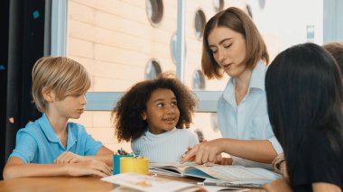 Masada masal kitabı ve renkli kitapla otururken çeşitli öğrencilere hikaye anlatan profesyonel beyaz bir öğretmen. Eğitmenden renkli resim alırken akıllı öğrenci dinlemeyi öğrenir. Etkinlik.