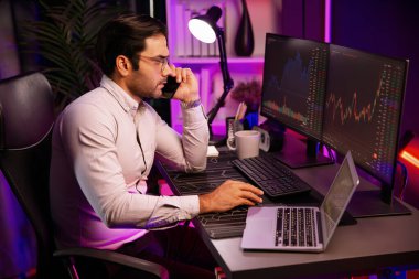 Tüccar akıllı işadamı komisyoncuyu ya da ortağını arıyor, modern evde kârlı bir finans teknolojisi olan neon aydınlatma ofisindeki bilgisayardaki dinamik borsa yatırımlarını analiz ediyor. Tahmin et..