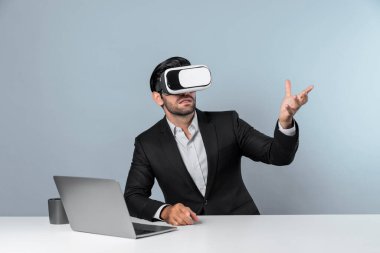 Bilgisayarla masada otururken ve VR gözlüğü takarken veri analizine bakan yetenekli bir iş adamı. Proje yöneticisi sanal gerçeklik sistemini kullanarak ya da metaevrende bağlantı kurarak çalışıyor. Sapma.