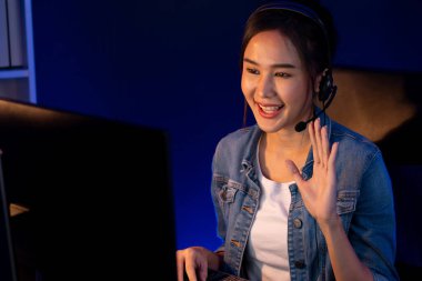 Sunucu kanalı Asyalı etkileyicisi canlı yayında konuşuyor. Sosyal medyada kulaklık takıyor, bilgisayar kaydı yapıyor, dinleyicileri selamlıyor ve Neon Modern Stüdyoları 'nda online olarak koçluk yapıyor. Taktik.