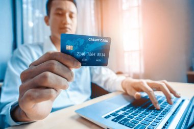 Genç adam, laptop bilgisayar başvurusu ya da web sitesinde online alışveriş yapmak için kredi kartı kullanıyor. E-ticaret ve online alışveriş konsepti. uds