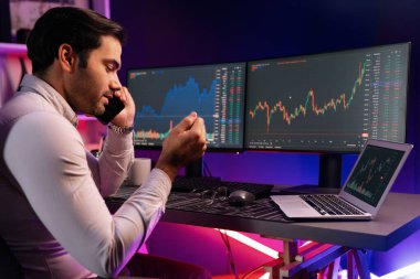 Tüccar akıllı işadamı komisyoncuyu ya da ortağını arıyor, modern evde kârlı bir finans teknolojisi olan neon aydınlatma ofisindeki bilgisayardaki dinamik borsa yatırımlarını analiz ediyor. Tahmin et..