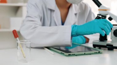 Laboratuvar kimya araştırmacısı mikroskop kullanarak yeni ilaç ya da tedavi geliştirir. Laboratuvar mikrobiyoloji ekipmanları ile bilimsel uzmanlık ile sağlık hizmetlerinin teknolojik gelişimi. Ağır çekim. Katı.