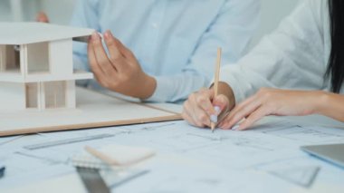 Profesyonel mühendis ev modelini tartartarken, yetenekli tasarımcı da planına yazar. Birlikte çalışmak, işbirliği, işbirliği. Yaratıcı tasarım ve takım çalışması konsepti. - Yakın çekim. Tertemiz.