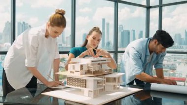 Beyaz proje yöneticisi dizüstü bilgisayar analiz verilerini kullanırken, mimar mühendis ekibi ev modeli inşaatını analiz etmek için birlikte çalışıyor. Bir grup tasarımcı ev tasarımı hakkında konuşuyor. İzleme