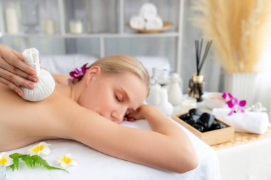 Sıcak bitkisel top spa masaj vücut tedavisi, masör kadın vücuduna nazikçe şifalı bitki torbası bastırıyor. Aromaterapi dinlenme sükuneti ve sükuneti kaplıca salonundaki atmosferi aydınlatıyor. Sessiz.